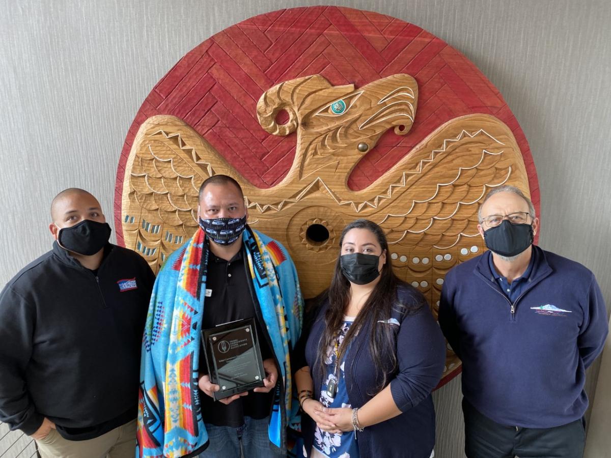 4 people standing and holding up a plaque.